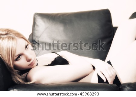 Portrait of young beautiful fair-haired woman having  rest on  sofa in underwear