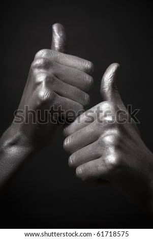 human silver hand with a thumb up on black background