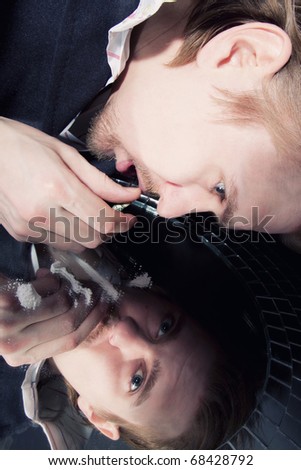 face of men inhaling cocaine powder on a mirror closeup