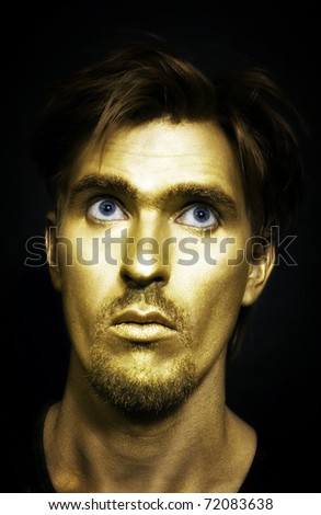 young attractive blue-eyed men with gold makeup on her face and stylish hairstyle on black background