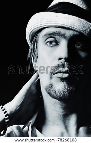 studio portrait of handsome young man in white hat on black background closeup