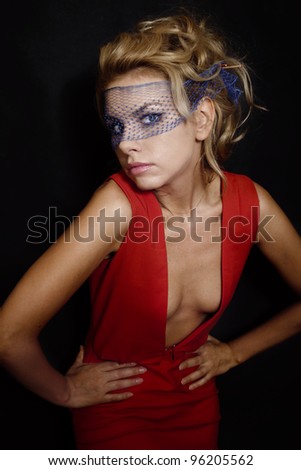 Portrait of beautiful young blonde woman with curly blond hair in red dress and veil on black background