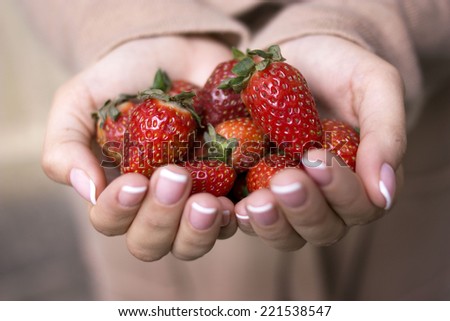 A handful of ripe strawberries in hands