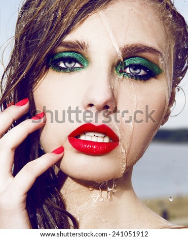 Close up Wet beautiful woman face with water drop.Bright make up.Red lips and green shadow. Moisturizing.