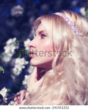 Fashion Beauty Blonde Model Girl with Beautiful spring girl in blooming tree  Flowers .Green eyes.Bride. Perfect Creative Make up and Hair Style. Hairstyle.