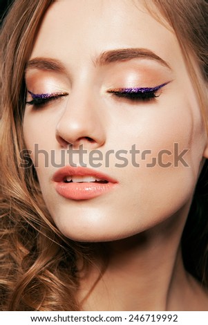 Beautiful woman with bright make up eye with sexy purple sparky gloss liner makeup. Fashion big arrow shape on woman\'s eyelid. Chic evening make-up, healthy face