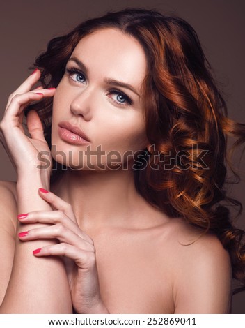 Hair. Beauty Woman with Very Long Healthy and Shiny Curly Red Hair. Model Red Girl Portrait isolated on a brown background. Gorgeous Hair