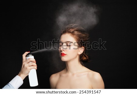 Young beautiful sexy girl with stylish make-up, red lips and hair, on black background, Hair salon. Woman haircut. Spraying