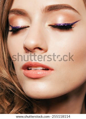 Beautiful woman with bright make up eye with sexy violet liner makeup. Fashion glitter arrow shape on woman\'s eyelid. Chic evening make-up