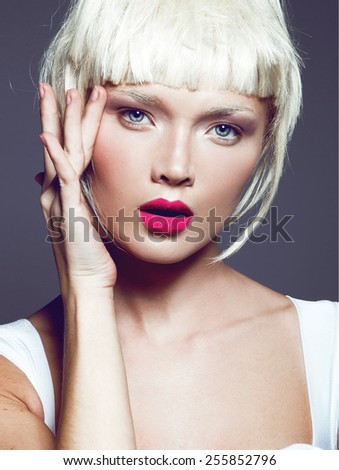 portrait of a beautiful woman in short blond bob wig with bright make-up, red lips,red nails,pretty young girl