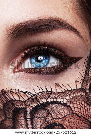 Blue eyes closeup.Beautiful fashion girl with arrow make up. Closeup female eye with beautiful fashion bright makeup,lace on the face