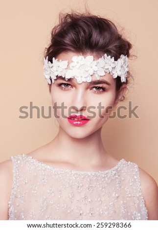 Bride.Young fashion model with perfect skin and make up, beige background, curly hair, flowers in hair