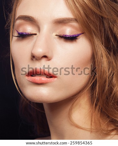 Beautiful woman with bright make up eye with sexy purple sparky gloss liner makeup. Fashion big arrow shape on woman\'s eyelid. Chic evening make-up, healthy face,curly hair