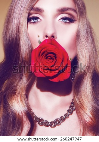Beauty Woman with Perfect Makeup. Red Lips and Nails. Beautiful Professional Holiday Makeup. Rose in the mouth