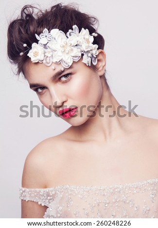Bride.Young fashion model with perfect skin and make up, grey background, curly hair, flowers in hair