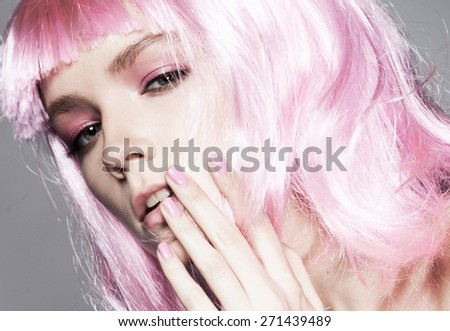 Close-up portrait of beautiful model with bright make up, on grey background fashion party style, pink wig