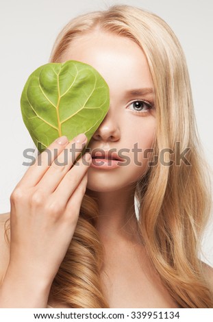 beautiful woman face portrait with green leaf , concept for skin care or organic cosmetics
