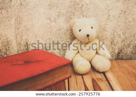 Book, teddy Bear on wooden and background of old wall. Soft focus, Process color.