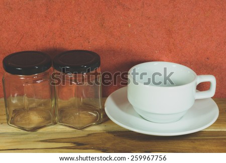 Empty coffee cup and empty jar on a wooden, Process color with Vintage Tones. Soft focus.