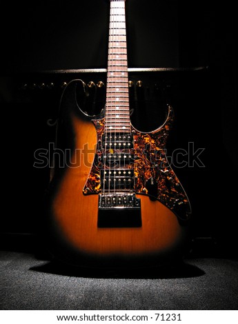 Guitar in front of amp lit up from spotlight on top