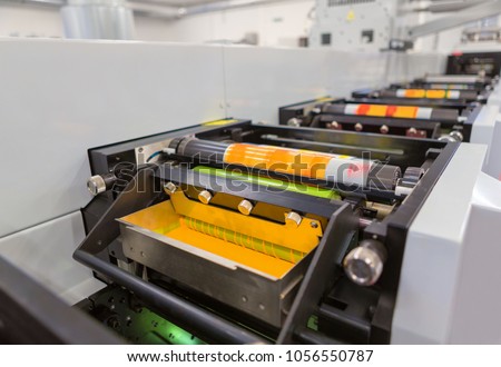 Flexographic printing machine with an ink tray, ceramic anilox roll, doctor blade and a print cylinder with polymer relief plate stuck on it. In-line press machine. Rotary or Flexo printing machine.