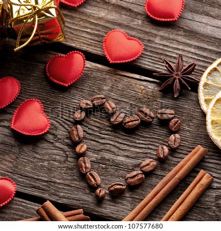 Coffee beans in shape of heart with cinnamon small red hearts and lemon on old vintage wooden background. Close-up.