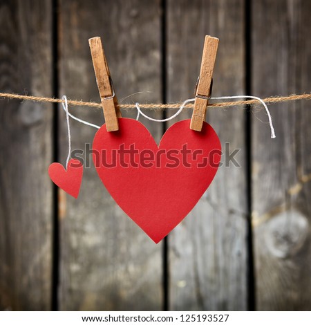Two lovely red hearts big and small hanging on the clothesline On old wood background Two lovely red hearts big and small hanging on the clothesline On old wood background