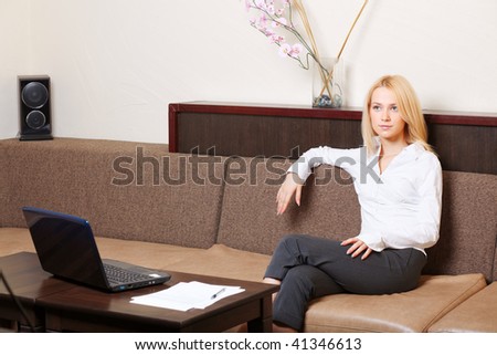 Businesswoman having a rest on the sofa in cozy interior, with laptop and documents.