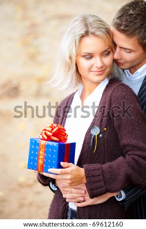 Happy young couple in love with a gift-box. They are smiling and embracing.