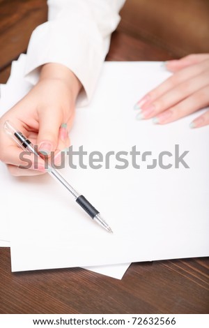 Woman hand showing (pointing) on blank white office paper by ball pen. Closeup.