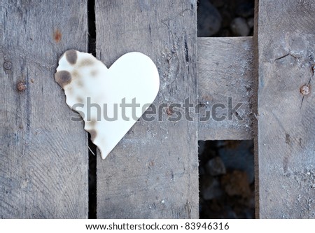 Partially burned paper heart shape on old wooden plates