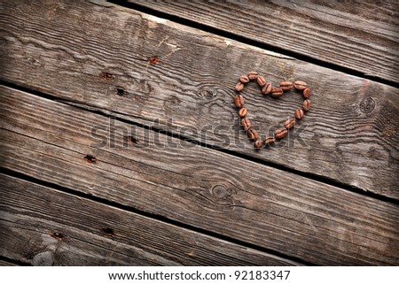 Coffee beans in shape of a heart, on old vintage wooden background.