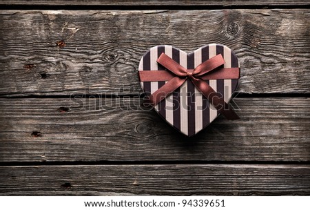 Heart shaped Valentines Day gift box closeup on old wood. Vintage holiday background.