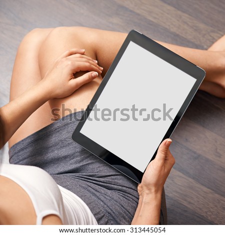 Woman using tablet computer while sitting on a wooden floor. View from above. Clipping path included.