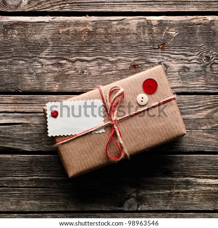 Vintage gift box package with blank gift tag on old wooden background Vintage gift box package with blank gift tag on old wooden background