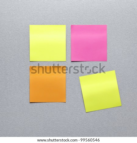 Blank different colors sticky note paper. On gray textured paper background. Closeup.