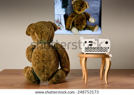Teddy Bear watching his photos with a mini projector. The transfer of the image is wireless.
