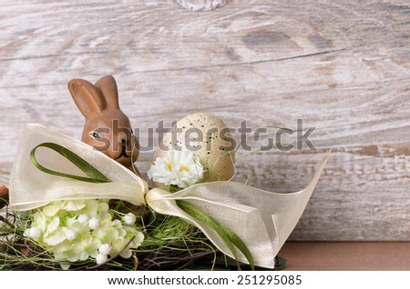 Easter bunny with easter egg in the nest against wooden background as an Easter greeting with free text space