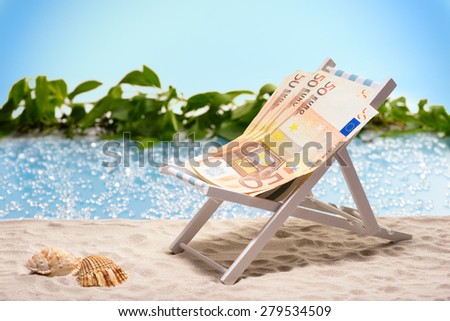 Money on vacation, pack of fifty Euro bills sitting at the beach on a sun lounger in front of a blue lagoon