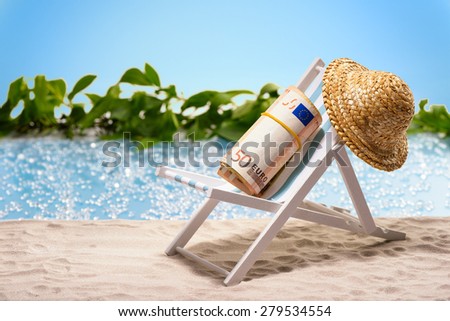 Money on vacation, pack of 50 Euro bills sitting at the beach on a sun lounger in front of a blue lagoon