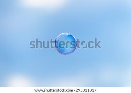 The whole world in a soap bubble. Soap bubble flying in front of the blue sky and mirroring the clouds.