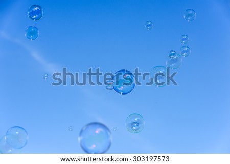 A bunch of soap bubbles flying up into the blue sky.