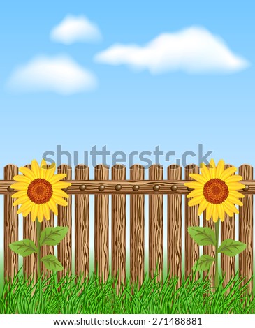 Wooden fence on grass with sunflower against the sky and clouds