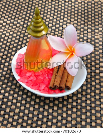 Tropical spa concept with plumeria flower, cinnamon, salts, and liqiud bottle