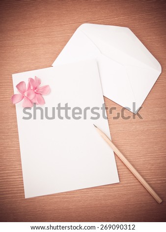 Pink flower with blank white paper on wooden floor, concept for writing a love letter