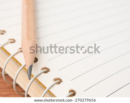 Sharp pencil on line notebook with wooden background