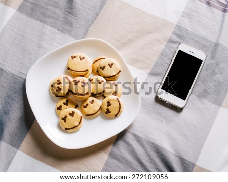 Homemade smile cookie with smart phone on the bed, Good morning concept, warm filter