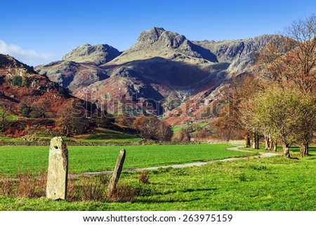Tall stones by the road to the Langdale Pikes. A couple of interesting stones stand by the path towards the magnificent Langdale Pikes as seen on a sunny autumn day.
