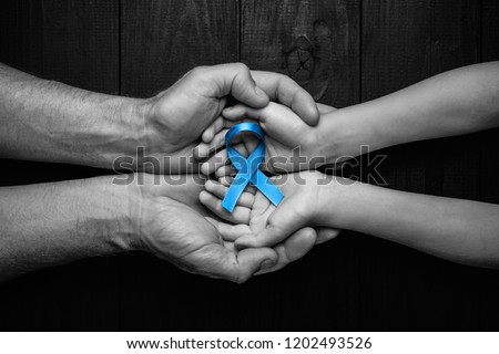 top view on hands holding prostate cancer ribbon, colon cancer concept, blue ribbon symbol.black and white.
