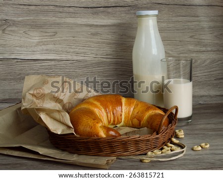 Croissant, bottle of milk and a glass of milk on a wooden background